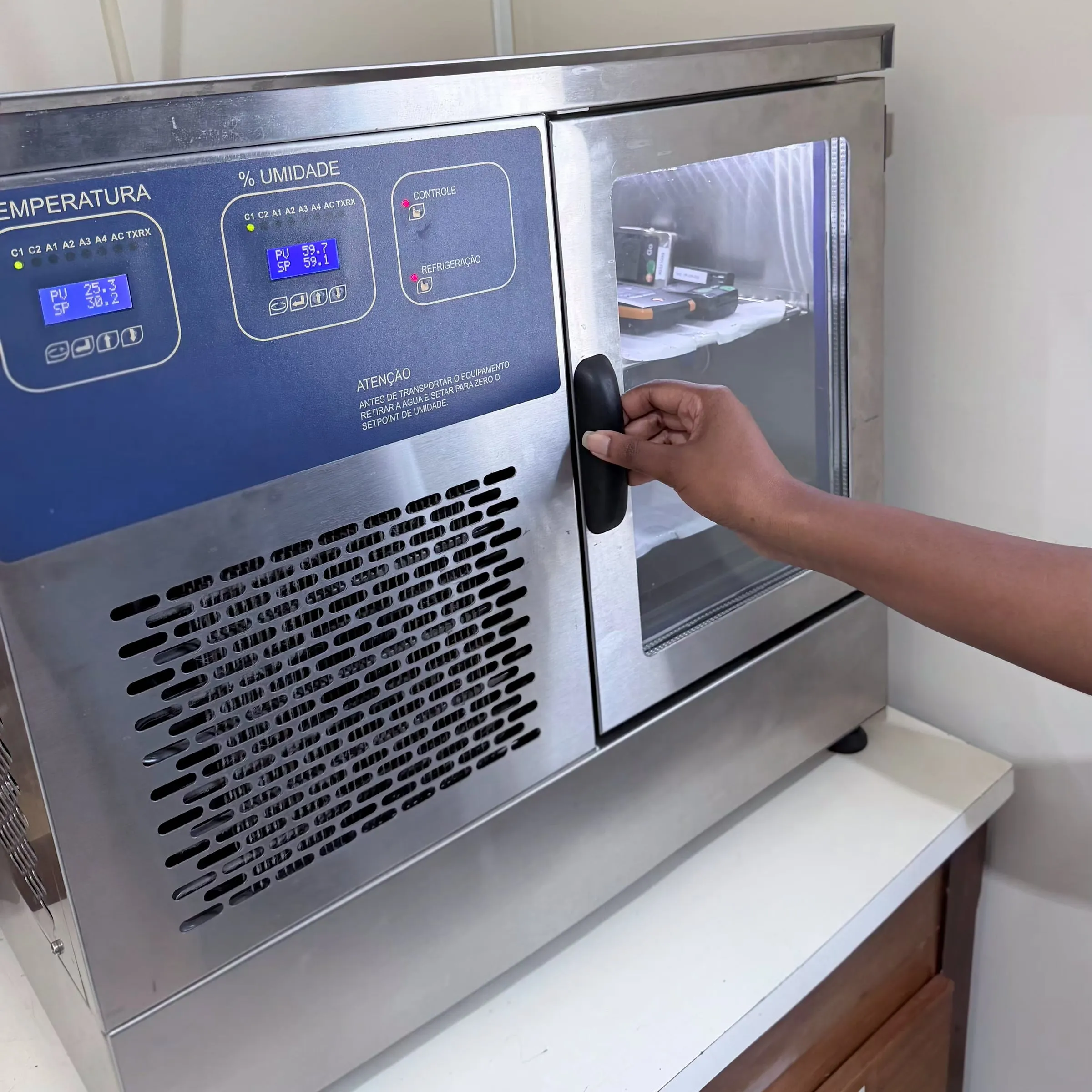 Câmara climática do laboratório sendo aberta, com os registradores de temperatura e umidade dentro.